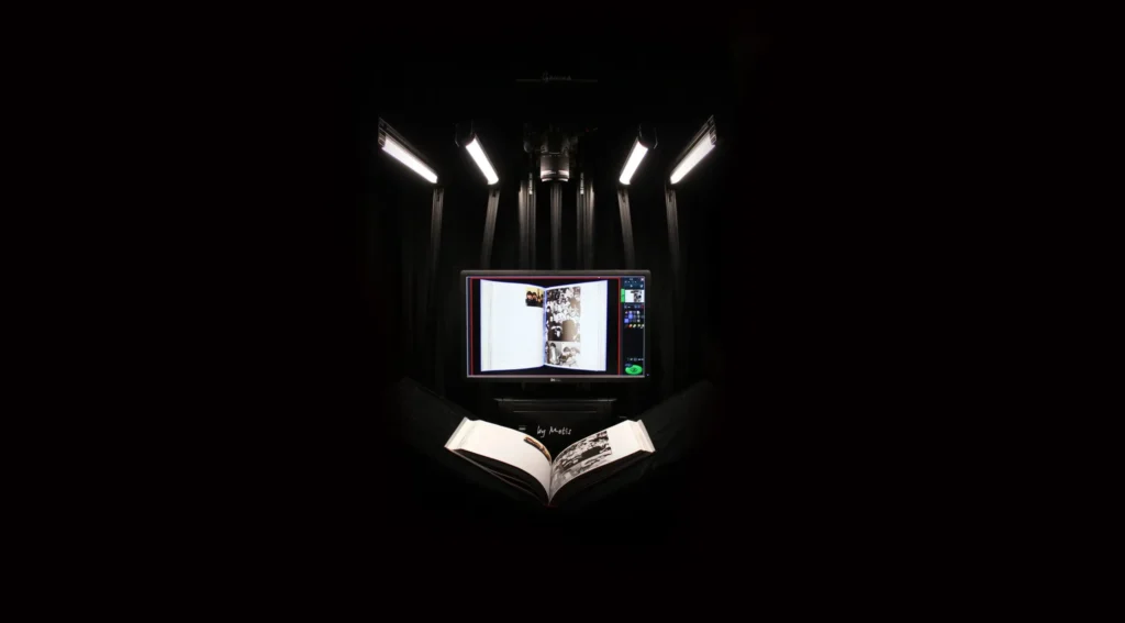 A photograph of a dark-lit book scanner with a book open.